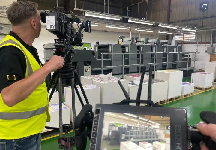Camera operator filming a printing machine in a factory for a video production in Milton Keynes